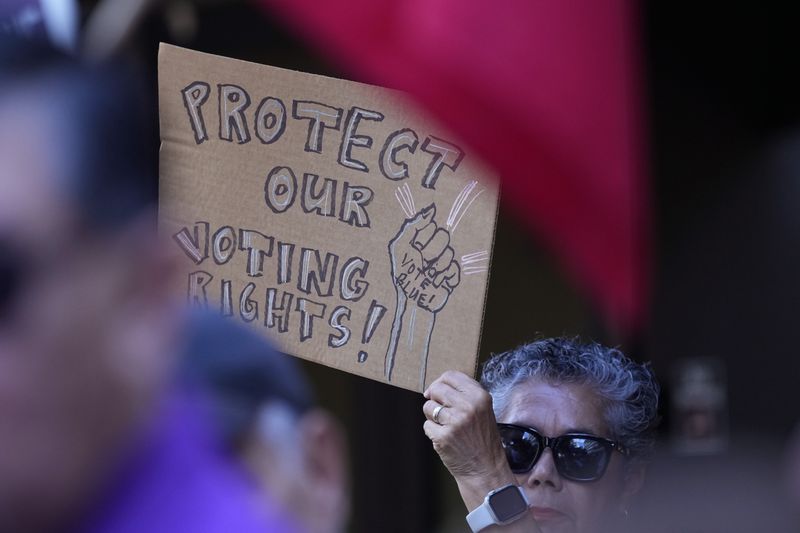 A supporter waves a sign at a news conference where Officials with the League of United Latin American Citizens, or LULAC, held a news conference to respond to allegations by Texas Attorney General Ken Paxton, Monday, Aug. 26, 2024, in San Antonio. (AP Photo/Eric Gay)