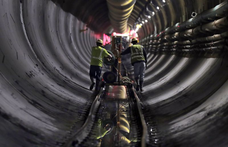 FILE - Tunnel workers push equipment up a rail track to a machine boring a 2.5-mile bypass tunnel for the Delaware Aqueduct in Marlboro, N.Y., May 16, 2018. (AP Photo/Julie Jacobson, File)