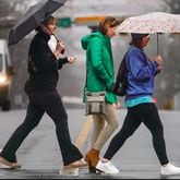 Three women walk across Tenth Street towards Piedmont Park on a rainy Tuesday. December 26th, 2023 (Ben Hendren for the Atlanta Journal-Constitution)