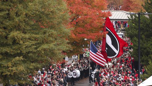 Cheerleaders carry the U.S. and the Georgia flag as they lead the Dawg Walk before Georgia’s game against Ole Miss at Sanford Stadium, Saturday, November 11, 2023, in Athens, Ga. (Jason Getz / Jason.Getz@ajc.com)