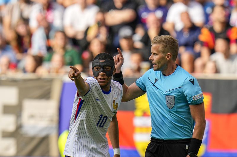 France's Kylian Mbappe, left, talks to Swedish referee Glenn Nyberg during a round of sixteen match between France and Belgium at the Euro 2024 soccer tournament in Dusseldorf, Germany, Monday, July 1, 2024. (AP Photo/Hassan Ammar)