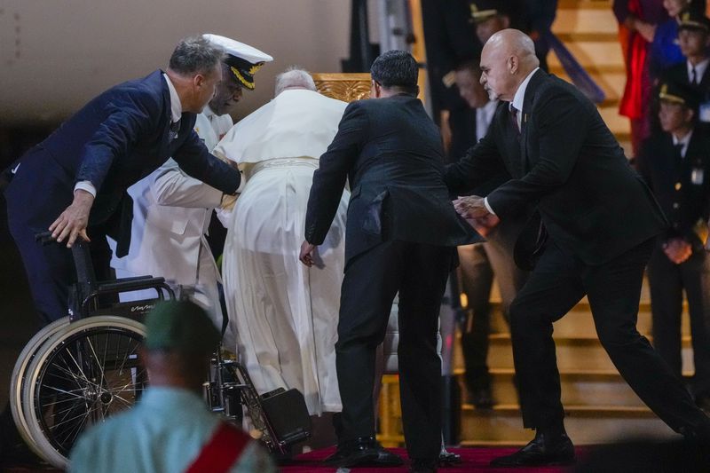 Papua New Guinea's deputy Prime Minister John Rosso, right, and rear-Admiral Philip Polewara, second from left, reach out to help Pope Francis keep his balance during a welcome ceremony at Port Moresby's "Jackson" International Airport, Friday, Sept. 6, 2024. As a second leg of his 11-day trip to Asia and Oceania Pope Francis's visit to Papua New Guinea will take him to a remote part of the South Pacific island nation where Christianity is a recent addition to traditional spiritual beliefs developed over millennia.(AP Photo/Gregorio Borgia)