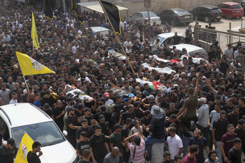 Mourners carry the bodies of Palestinian men who were killed during an Israeli military operation, some draped in the Palestinian and the Islamic Jihad militant group flags, during their funeral in Jenin, West Bank, Friday, Sept. 6, 2024. (AP Photo/Nasser Nasser)