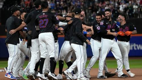 New York Mets players celebrate after Jeff McNeil hit a walkoff single leading Jose Iglesias to score during the 10th inning of a baseball game against the Atlanta Braves, Thursday, July 25, 2024, in New York. (AP Photo/Pamela Smith)