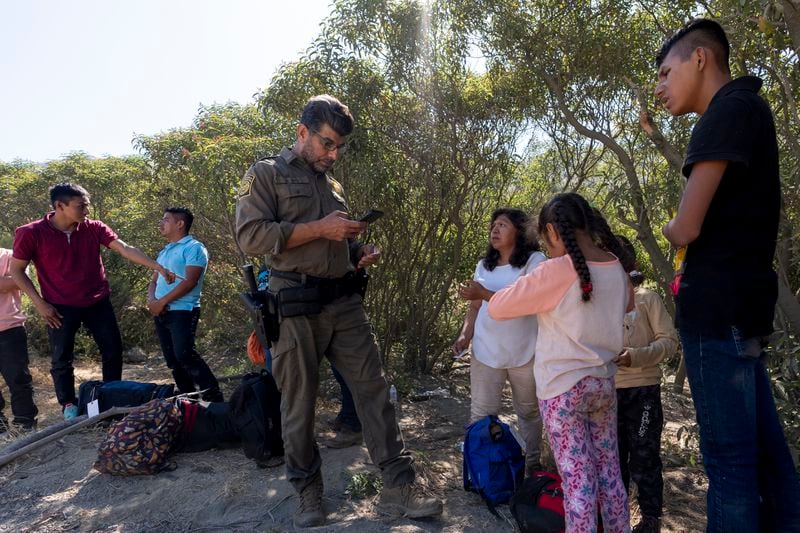 Border Patrol agents talk with migrants seeking asylum as they prepare them for transportation to be processed, Wednesday, June 5, 2024, near Dulzura, Calif. President Joe Biden on Tuesday unveiled plans to enact immediate significant restrictions on migrants seeking asylum at the U.S.-Mexico border as the White House tries to neutralize immigration as a political liability ahead of the November elections. (AP Photo/Gregory Bull)