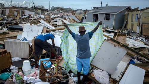 FILE - Immigrants from Haiti recover their belongings from the rubble in their destroyed homes, in the aftermath of Hurricane Dorian in Abaco, Bahamas, Sept. 16, 2019. (AP Photo/Ramon Espinosa, File)