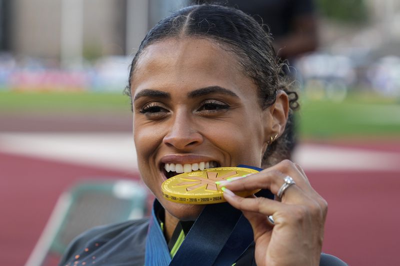 Sydney McLaughlin-Levrone bites down on her gold medal after winning the women's 400-meter hurdles final during the U.S. Track and Field Olympic Team Trials, Sunday, June 30, 2024, in Eugene, Ore. (AP Photo/Charlie Neibergall)