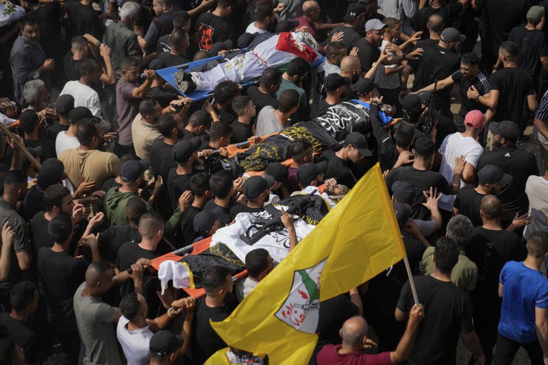 Mourners carry the bodies of Palestinian men who were killed during an Israeli military operation, some draped in the Palestinian and the Islamic Jihad militant group flags, during their funeral in Jenin, West Bank, Friday, Sept. 6, 2024. (AP Photo/Nasser Nasser)