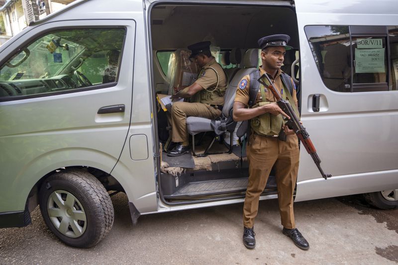 A police officer sits next to a sealed ballot box as polling officials prepare to return it to a counting center at the end of voting during presidential election in Colombo, Sri Lanka, Saturday, Sept. 21, 2024. (AP Photo/Rajesh Kumar Singh)