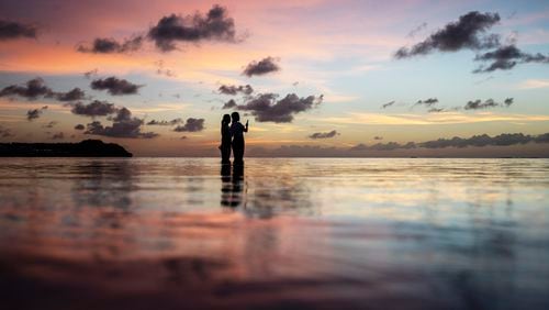 FILE - Tourists watch the sun set along a popular beach in Tamuning, Guam, May 6, 2019. (AP Photo/David Goldman, File)