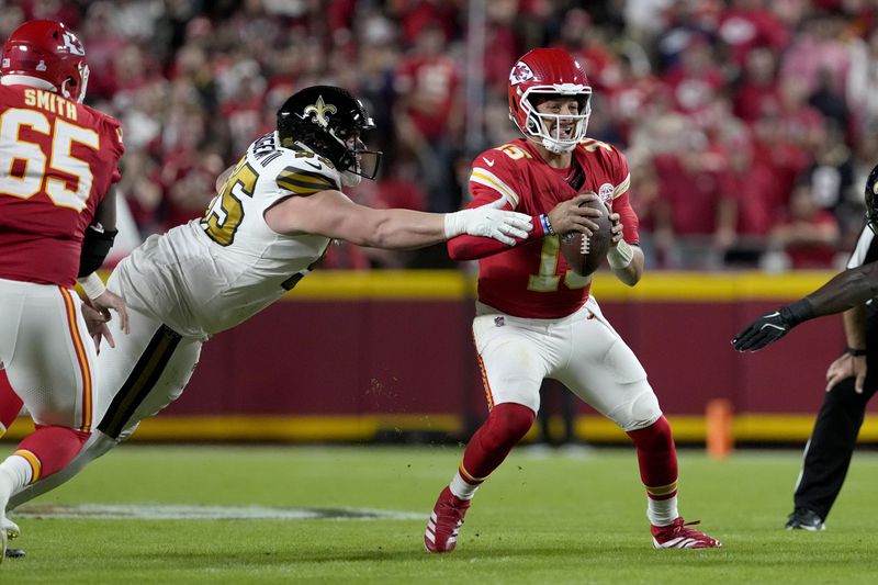 Kansas City Chiefs quarterback Patrick Mahomes, right, scrambles away from New Orleans Saints defensive tackle John Ridgeway III during the first half of an NFL football game Monday, Oct. 7, 2024, in Kansas City, Mo. (AP Photo/Ed Zurga)