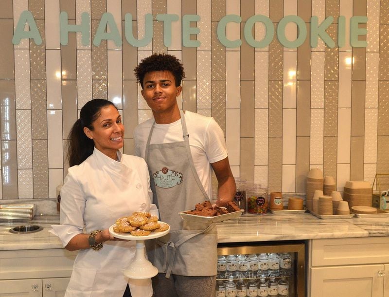 Shiana White (left), owner of A Haute Cookie, poses with son Cory Curtis, who works for A Haute Cookie, with White Chocolate Chunk Cookies with peppermint topping and brownies. CONTRIBUTED BY CHRIS HUNT PHOTOGRAPHY