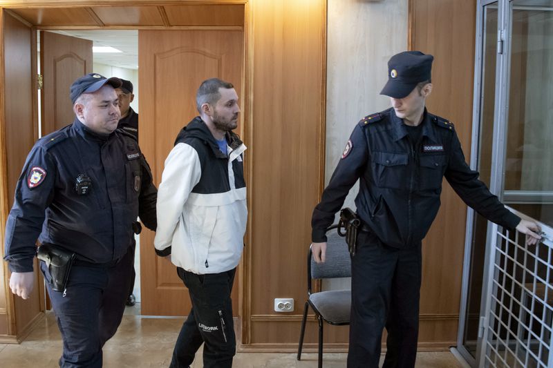 U.S. Army Staff Sgt. Gordon Black, center, is escorted into a glass cage at a courtroom in Vladivostok, Russia, Wednesday, June 19, 2024. Black is on trial on charges of theft and threatening murder in a dispute with a Russian woman. Russian state media reported that he denied the allegation of threatening murder but "partially" admitted to theft. (AP Photo)