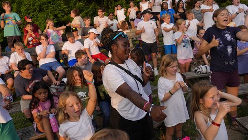Counselor Kendra Ashong, center, sings a song with other campers, Thursday, June 20, 2024, at YMCA Camp Kern in Oregonia, Ohio.As the first heat wave of the season ripples across the U.S., summer camps are working to keep their children cool while still letting the kids enjoy being outside with nature. (AP Photo/Joshua A. Bickel)