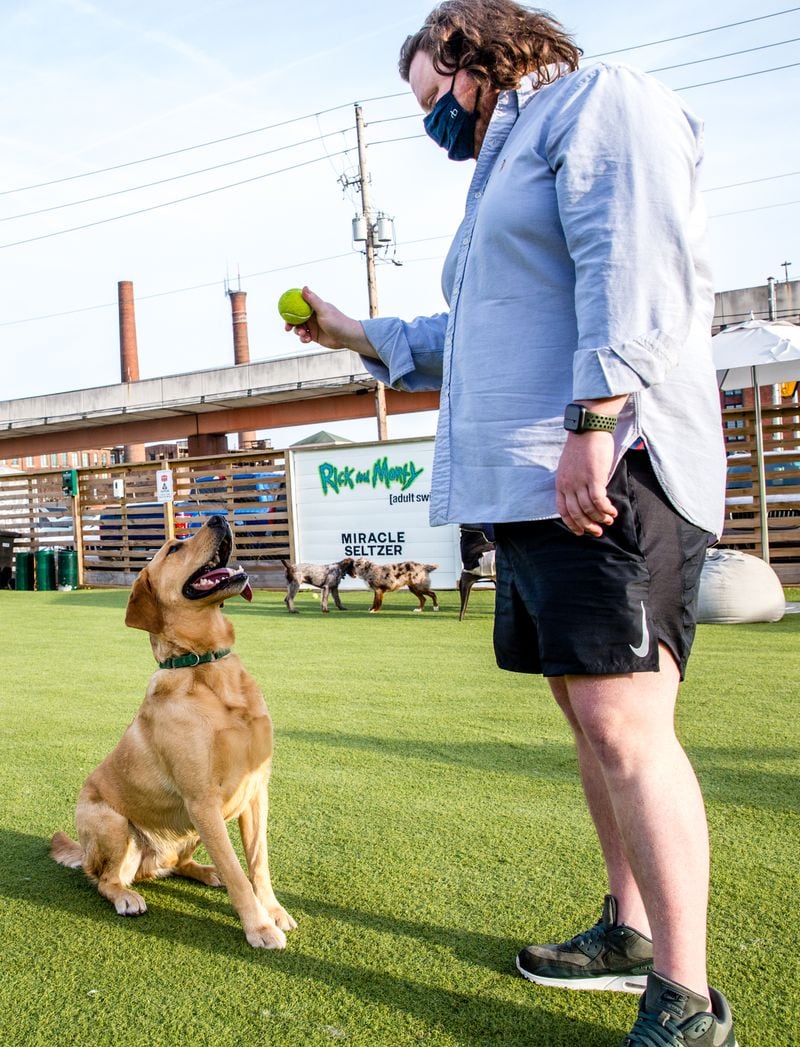 Matt Matuszewski and his yellow lab Murphy play at Fetch Park at Boulevard and DeKalb Ave on Friday,  March 12, 2021.  (Jenni Girtman for The Atlanta Journal-Constitution)