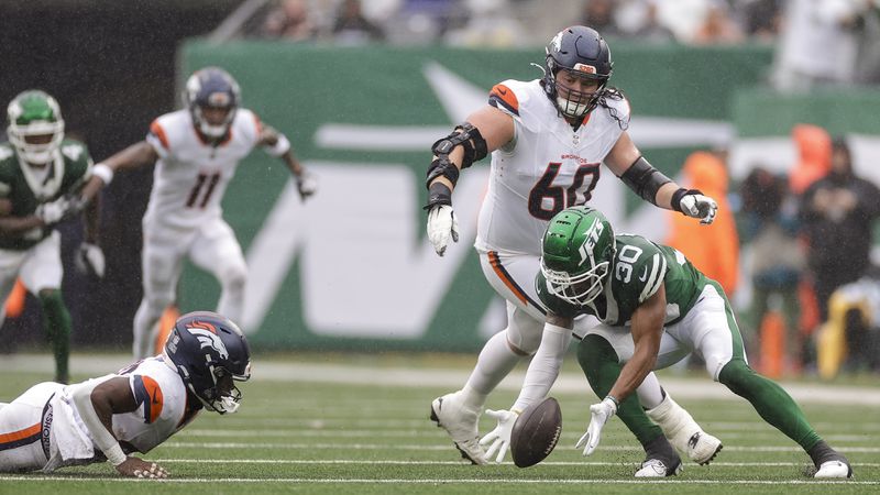 New York Jets cornerback Michael Carter II (30) recovers a fumble by Denver Broncos running back Tyler Badie (28) during the first quarter of an NFL football game, Sunday, Sept. 29, 2024, in East Rutherford, N.J. (AP Photo/Adam Hunger)