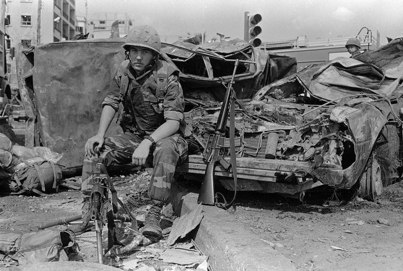 FILE - A U.S. Marine sits on the bumper of a car that was destroyed when a huge bomb explosion wrecked the American Embassy in West Beirut, on April 19, 1983. (AP Photo/Bill Foley, File)