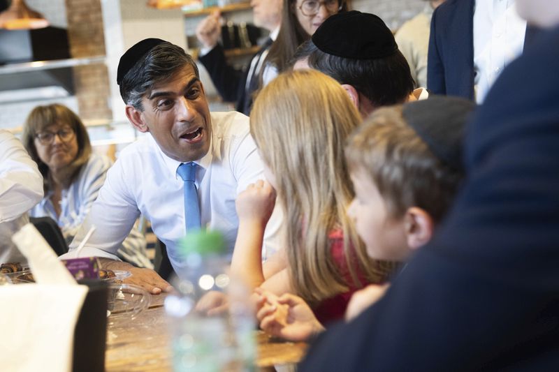 Britain's Prime Minister Rishi Sunak speaks with local children during a visit to a bakery in Golders Green, while on the general election campaign trail, in north west London, Sunday June 30, 2024. (James Manning/Pool Photo via AP)