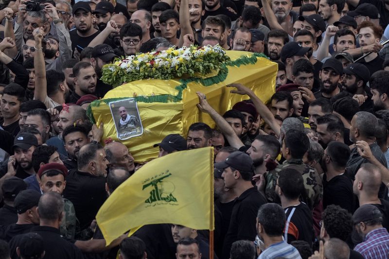 Mourners carry the coffin of Mohammed Mahdi, son of Hezbollah legislator Ali Ammar, who was killed Tuesday after his handheld pager exploded, in the southern suburb of Beirut, Lebanon, Wednesday, Sept. 18, 2024. (AP Photo/Bilal Hussein)