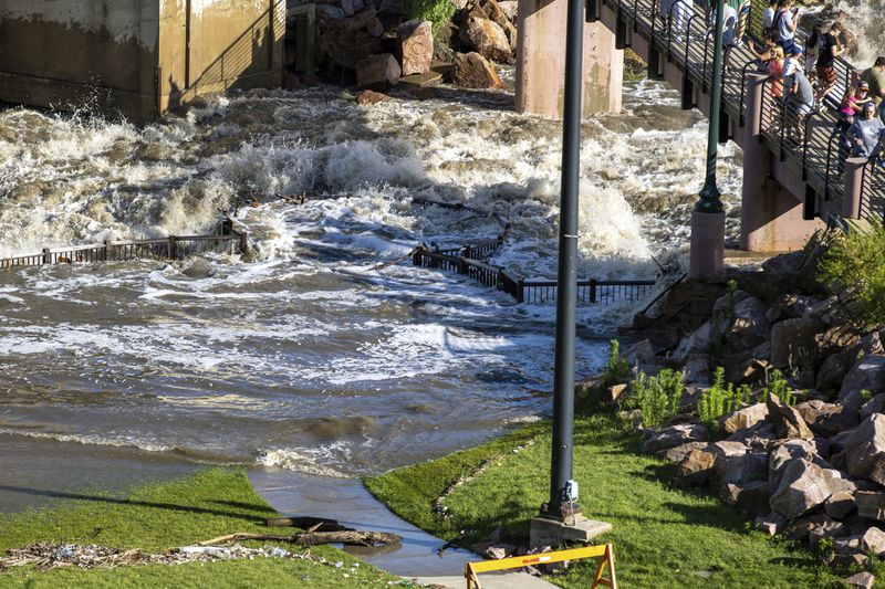 People on a viewing platform watch as Falls Park in Sioux Falls, S.D, was underwater on Saturday, June 22, 2024, after days of heavy rain led to flooding in the area. (AP Photo/Josh Jurgens)