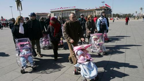 FILE- Spanish couples take their newly adopted Chinese children for a walk in Beijing's Tiananmen Square, March 7, 2007. (AP Photo/Greg Baker, File)