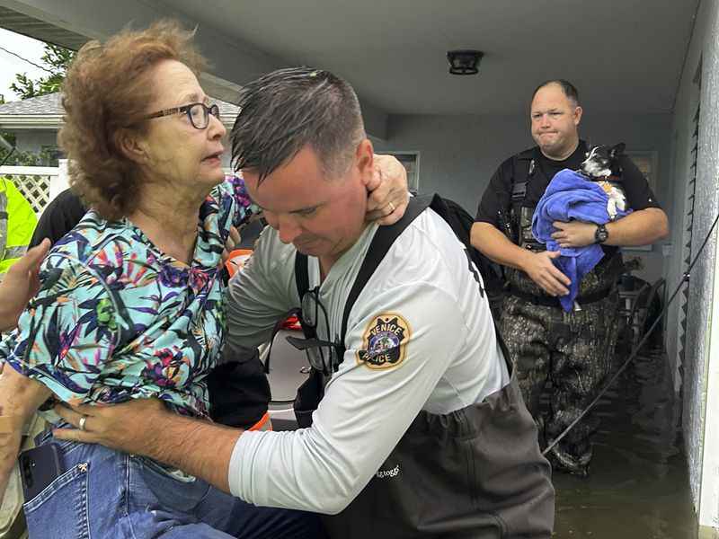 This photo provided by Venice Police Department rescue crews assist residents after conducting door-to-door wellness checks, in coastal areas that were flooded by Hurricane Helene on Friday, Sept. 27, 2024 in Venice, Fla . (Venice Police Department via AP)