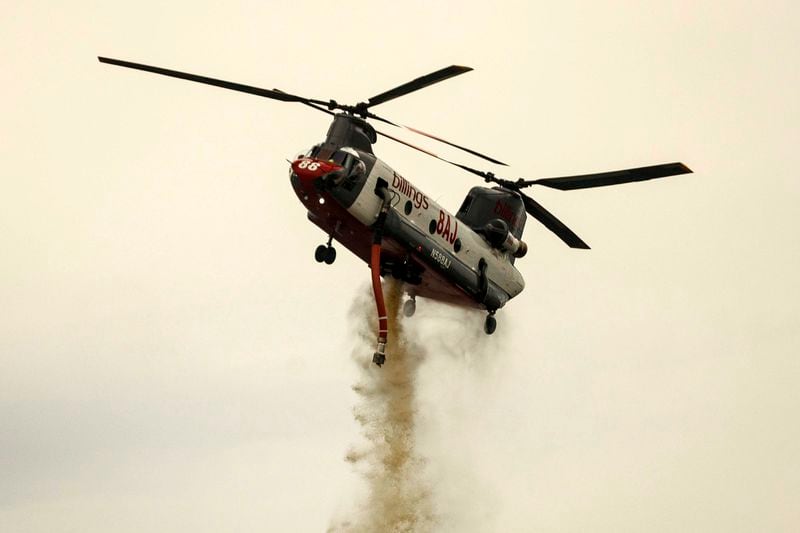 A helicopter drops water on the Apache Fire as it burns in Palermo, Calif., on Tuesday, Jun. 25, 2024. According to Cal Fire, more than a dozen new fires sparked by lightning. (AP Photo/Ethan Swope)