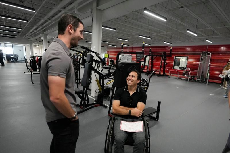 Auto racing drivers Alexander Rossi, left, and Robert Wickens talk following a ribbon-cutting ceremony for the not-for-profit Conquer Paralysis Now center Tuesday, Oct. 1, 2024, in Indianapolis. (AP Photo/Darron Cummings)