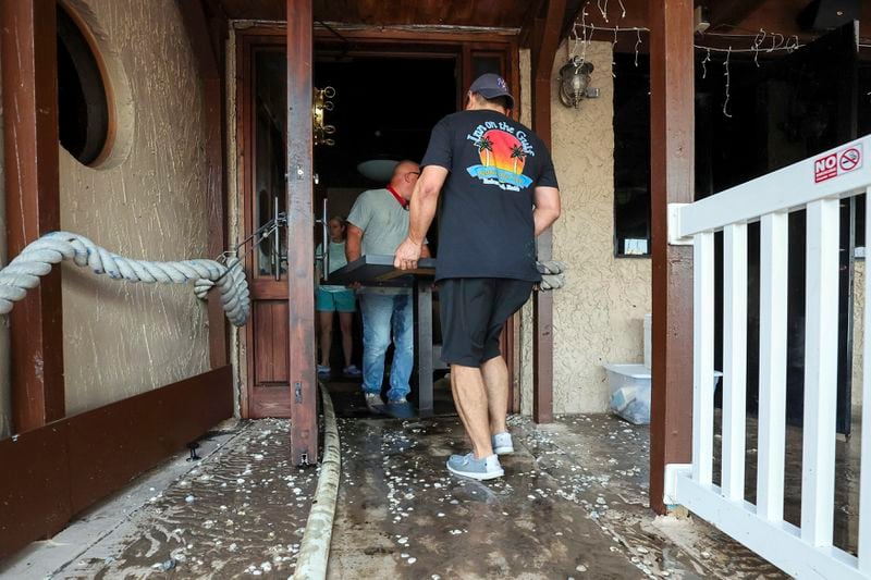 Staff of the Inn On The Gulf clean up after their restaurant flooded with surge from Hurricane Helene Friday, Sept. 27, 2024, in Hudson, Fla. (AP Photo/Mike Carlson)