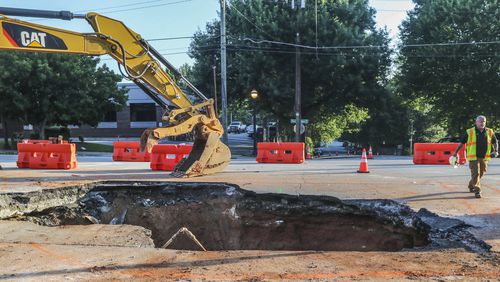 June 28, 2023 Atlanta: One day after a massive sinkhole opened along one of the most traveled roads in Midtown Atlanta, swallowing an SUV, traffic was moving again on Wednesday, June 28, 2023. Crews were still digging out dirt and temporary roadblocks remain in place on Ponce de Leon Avenue, but at least one eastbound lane and two westbound lanes are open. The portion of road between Myrtle Street and Argonne Avenue had been closed to traffic since Tuesday afternoon to repair a broken sewer pipe that caused the surface to collapse. Officials with the city’s department of watershed management described the culprit as a “breach” in the pipe about 15 to 18 feet below the surface but did not elaborate further. Crews worked at the site overnight excavating the hole and making the repairs. A spokesperson for the department said there is no estimated time of completion. Atlanta police said they received a call just before 2:15 p.m. Tuesday about the vehicle that fell into a hole at 265 Ponce de Leon Avenue, in front of Torched Hop Brewery and across the street from Mary Mac’s Tea Room. The area is located just east of Piedmont Avenue. Photos showed the front of the white Ford Expedition tilted diagonally inside the sinkhole, with only its rear tires still on a level surface. According to Channel 2 Action News, the driver was trying to make a right turn when the vehicle fell in. He managed to climb out of the driver’s-side window, while his wife escaped out of a back door. (John Spink / John.Spink@ajc.com)

