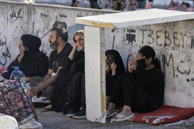 Families sit on the ground in Martyrs' square after fleeing the Israeli airstrikes in Beirut's southern suburbs, Saturday, Sept. 28, 2024. (AP Photo/Bilal Hussein)