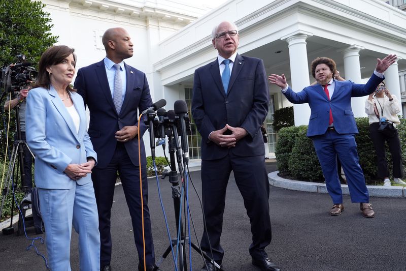 A staff member gestures for governors to finish answering questions from reporters, as from left, New York Gov. Kathy Hochul, Maryland Gov. Wes Moore and Minnesota Gov. Tim Walz listen after they met with President Joe Biden, Wednesday, July 3, 2024, at the White House in Washington. (AP Photo/Susan Walsh)
