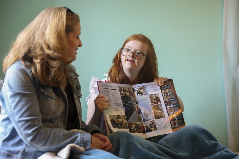 Darden Glass shows her mother Betsy Glass a page in her high school’s yearbook. Darden takes special education classes at her local high school and will likely graduate in the next couple of years. (Jason Getz / Jason.Getz@ajc.com)