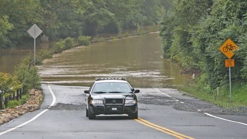 A police officer blocks the entrance to Azalea Drive in Roswell, which runs along the Chattahoochee River, on Sept. 22, 2009. (Photo: Bob Andres, bandres@ajc.com )
