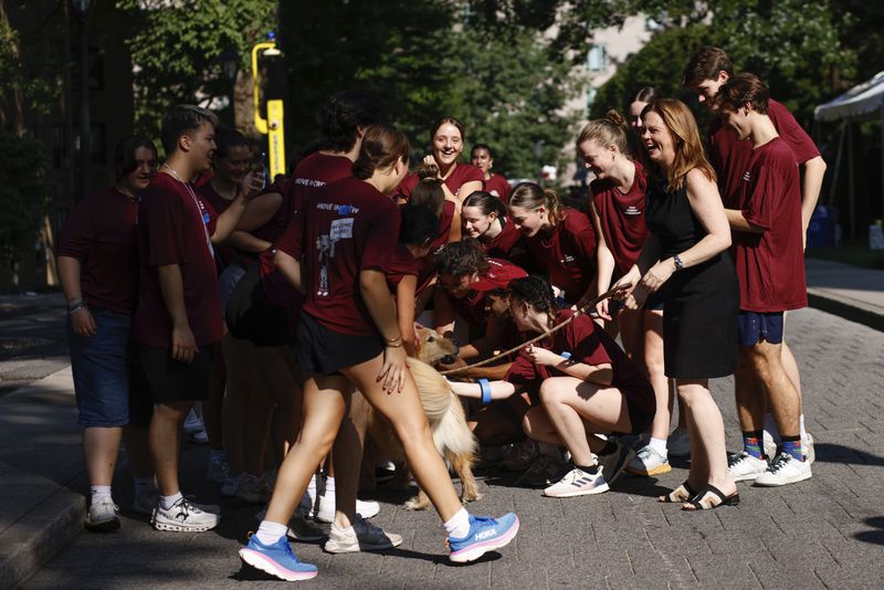 Tania Tetlow, president of Fordham University, holds her dog Archie as she meets students during Move In Day at the Bronx campus, Sunday, Aug. 25, 2024, in New York. (AP Photo/Kena Betancur)