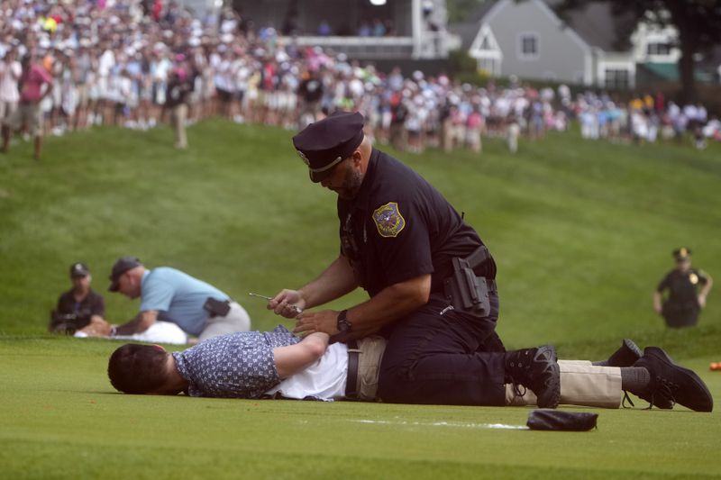 Protesters are taken into custody after they ran onto the course on the 18th hole during the final round of the Travelers Championship golf tournament at TPC River Highlands, Sunday, June 23, 2024, in Cromwell, Conn. (AP Photo/Seth Wenig)