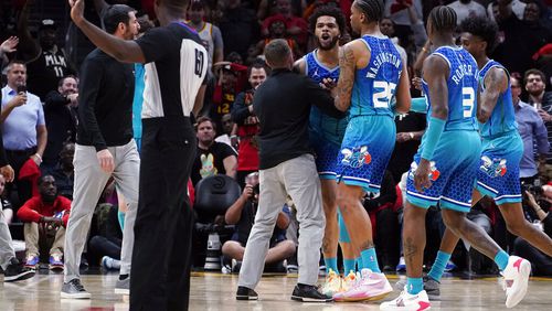 Charlotte Hornets forward Miles Bridges (0) is restrained by P.J. Washington (25) and others as he argues with an official after being charged with a foul during the second half of the team's NBA play-in basketball game against the Atlanta Hawks on Wednesday, April 13, 2022, in Atlanta. Bridges was ejected. (AP Photo/John Bazemore)