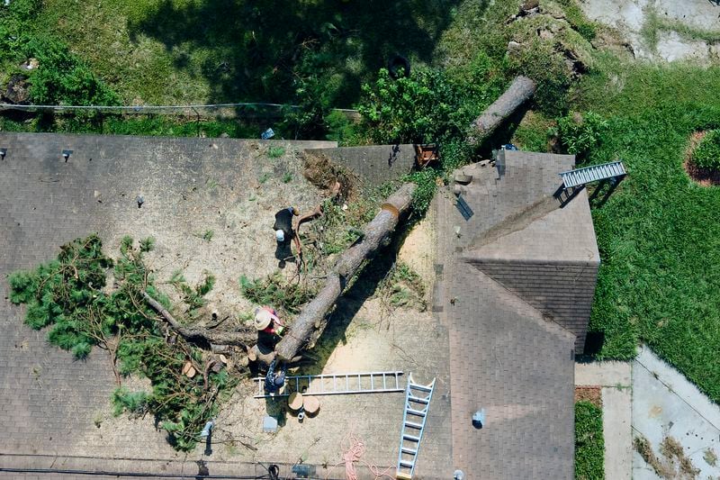 Employees of Premier Home Improvement remove a tree from the roof of a house in the aftermath of Hurricane Beryl in the Homestead neighborhood of Houston on Wednesday, July 10, 2024. (Elizabeth Conley/Houston Chronicle)