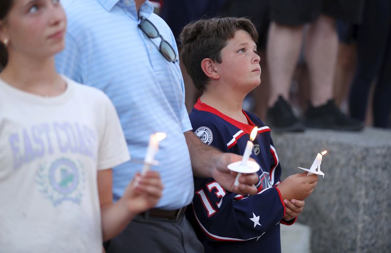 Blue Jackets fan Hudson Saad of Columbus, has a moment of silence during the candlelight vigil to honor Columbus Blue Jackets hockey player Johnny Gaudreau, outside of Nationwide Arena in Columbus, Ohio, Thursday, Sept. 4, 2024. Gaudreau and his brother Matthew were killed by a motor vehicle last week while riding bicycles. (AP Photo/Joe Maiorana)