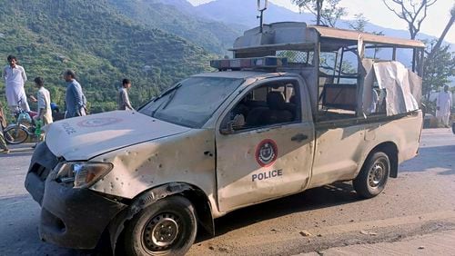 People gather near a damaged police vehicle which was escorting a convoy of foreign diplomats, at the site of a fatal bomb explosion on a road near Malam Jabba, a tourist area in Pakistan's Khyber Pakhtunkhwa province, Sunday, Sept. 22, 2024. (AP Photo/Sherin Zada)