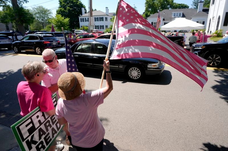 Carol Kelly, of Canton, Mass., below right, waves a pink and white American flag in support of Karen Read while Gail White, of Canton, left, holds a sign, a block from Norfolk Superior Court, Tuesday, June 25, 2024, in Dedham, Mass. Karen Read is on trial, accused of killing her boyfriend Boston police Officer John O'Keefe, in 2022. (AP Photo/Steven Senne)