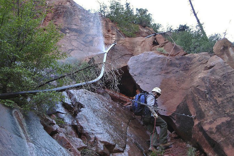 FILE - In this undated photo provided by the National Park Service shows a water spraying from a break in an exposed section of the Grand Canyon trans-canyon waterline as a worker attempts repairs. (National Park Service via AP, File)