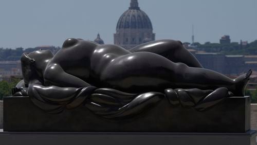 Botero's "Sleeping Venus" sculpture, installed in Rome's Pincio Terrace, Friday, July 19, 2024, appears to be in front of St. Peter's Basilica at The Vatican. Rome's storied streets and piazzas have become a vibrant canvas for Fernando Botero's exuberant sculptures, turning the city into an open-air museum of voluminous forms and daring artistry. (AP Photo/Gregorio Borgia)