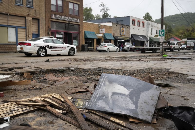 A Madison County sheriff's vehicle passes damaged buildings along Bridge Street in the aftermath of Hurricane Helene Tuesday, Oct. 1, 2024, in Hot Springs, N.C. (AP Photo/Jeff Roberson)