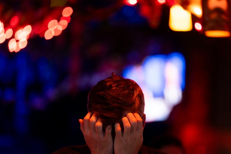 A patron, who wished to remain unnamed, puts their head in their hands as people watch a presidential debate at Hula Hula, a tiki themed karaoke bar, Thursday, June 27, 2024, in Seattle. (AP Photo/Lindsey Wasson)