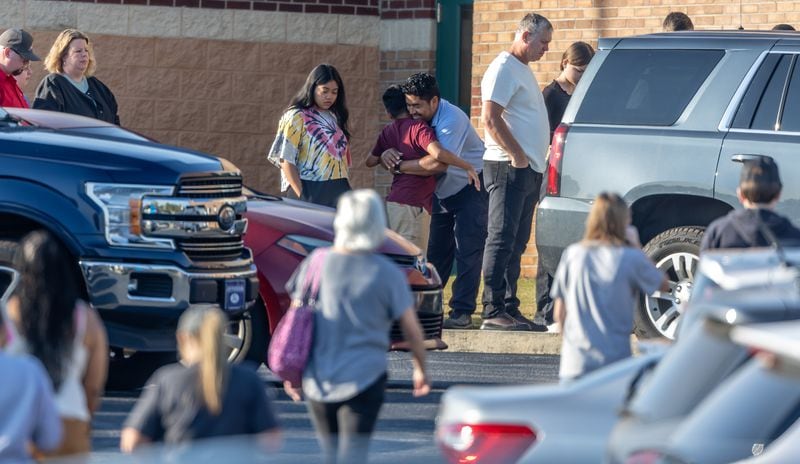 A parent hugs a child outside Apalachee High School on Monday.