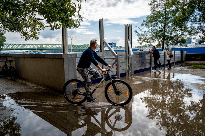 A man riding a bicycle is reflected in water infiltrated through anti-flood barriers on the banks of the River Danube, in Bratislava, Slovakia, Tuesday, Sept. 17, 2024. (AP Photo/Tomas Hrivnak)