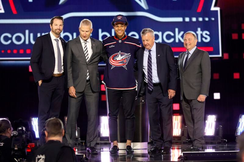 Cayden Lindstrom, center, poses after being selected by the Columbus Blue Jackets during the first round round of the NHL hockey draft Friday, June 28, 2024, in Las Vegas. (AP Photo/Steve Marcus)