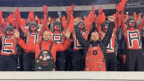 Mike Woods Jr. (front left in black overalls), known as Little Mike, and his brother Trent Woods (front right in red overalls) join the University of Georgia paint line to cheer on the Bulldogs in their game against Auburn on Oct. 8, 2022 at Sanford Stadium in Athens. The Woods brothers have been keeping alive the family tradition of painting one's bald head with the UGA logo. Trent Woods died in February 2024. (Photo courtesy of Mike Woods)