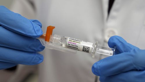 A pharmacist holds a COVID-19 vaccine at a pharmacy in New York, Tuesday, Sept. 24, 2024. (AP Photo/Mary Conlon)